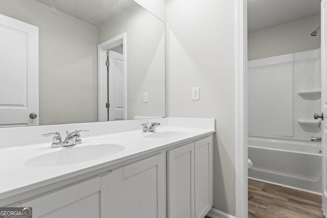 bathroom with double vanity, wood finished floors, a sink, and toilet