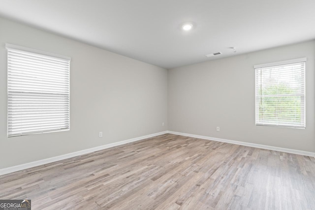 empty room featuring visible vents, light wood-style flooring, and baseboards