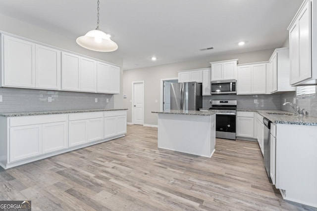 kitchen featuring sink, stainless steel appliances, light stone countertops, white cabinets, and a kitchen island