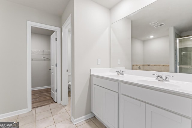 full bathroom featuring a stall shower, visible vents, tile patterned flooring, a spacious closet, and a sink