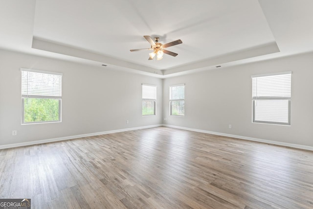 unfurnished room with a tray ceiling and light wood-type flooring