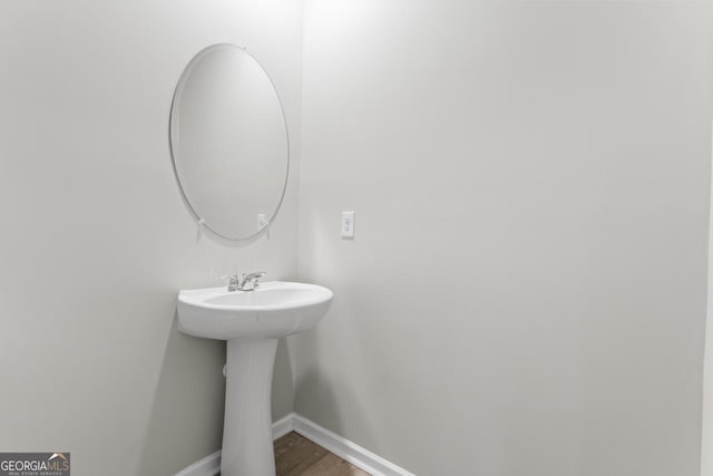 bathroom featuring a sink, baseboards, and wood finished floors