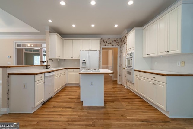 kitchen with a center island, white appliances, and white cabinets