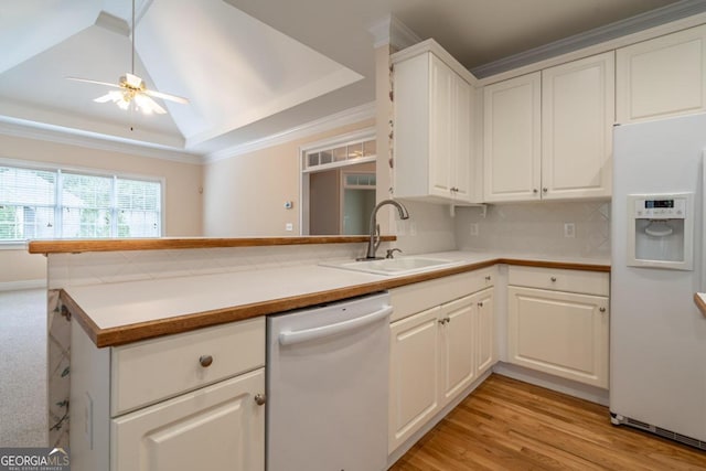 kitchen with kitchen peninsula, sink, a raised ceiling, white cabinetry, and white appliances