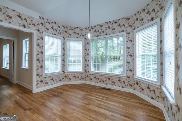 unfurnished dining area featuring ornamental molding, hardwood / wood-style flooring, and a healthy amount of sunlight