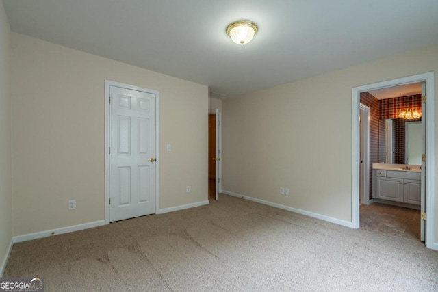 unfurnished bedroom featuring ensuite bathroom and light colored carpet