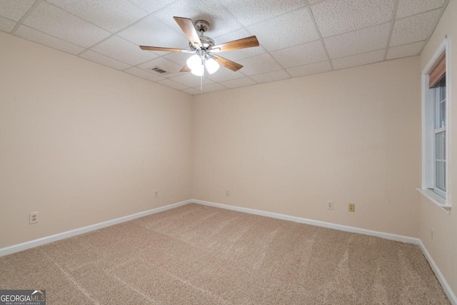 carpeted empty room with ceiling fan and a paneled ceiling