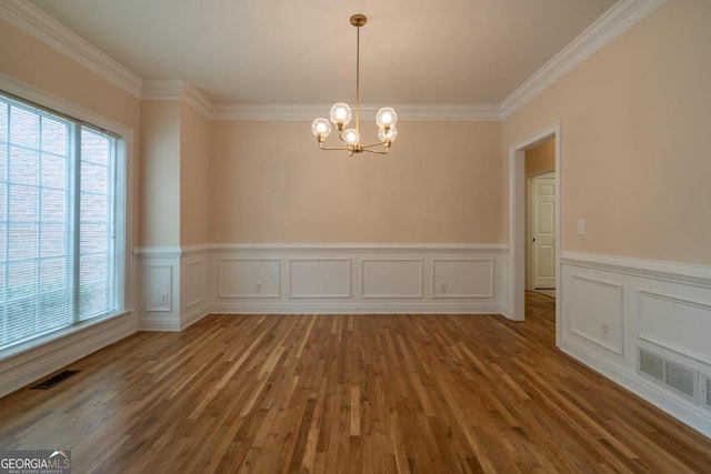 unfurnished dining area featuring a notable chandelier, hardwood / wood-style floors, and crown molding