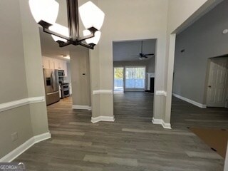 unfurnished dining area with dark hardwood / wood-style floors and ceiling fan with notable chandelier