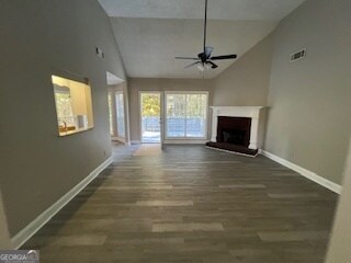 unfurnished living room with ceiling fan, high vaulted ceiling, and dark hardwood / wood-style flooring