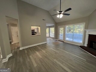 unfurnished living room with dark hardwood / wood-style floors, high vaulted ceiling, and ceiling fan