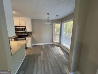 kitchen with hardwood / wood-style floors, appliances with stainless steel finishes, decorative light fixtures, and white cabinetry