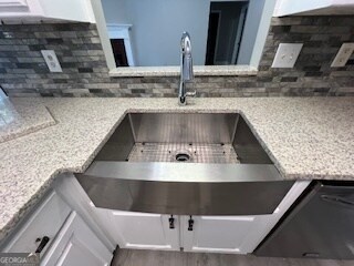 details featuring decorative backsplash, white cabinetry, light stone countertops, and sink