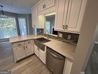 kitchen featuring kitchen peninsula, white cabinetry, and stainless steel dishwasher