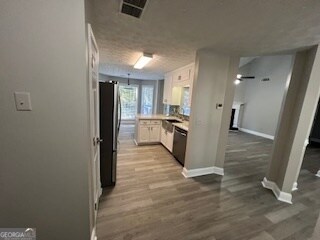 kitchen featuring appliances with stainless steel finishes, white cabinets, and hardwood / wood-style flooring