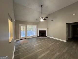 unfurnished living room with dark wood-type flooring, high vaulted ceiling, and ceiling fan