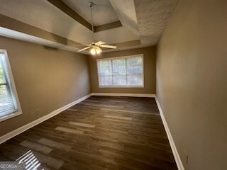 spare room featuring ceiling fan, a tray ceiling, and dark hardwood / wood-style flooring