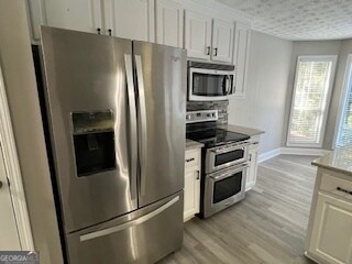 kitchen featuring white cabinetry, light hardwood / wood-style floors, and stainless steel appliances