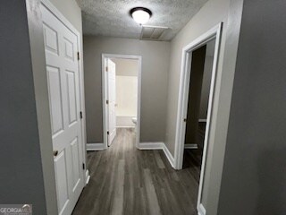 corridor with dark wood-type flooring and a textured ceiling