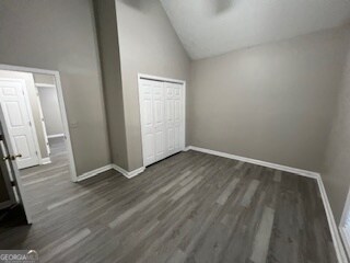 unfurnished bedroom with a closet, dark hardwood / wood-style floors, and high vaulted ceiling