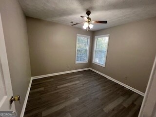 spare room featuring a textured ceiling, dark wood-type flooring, and ceiling fan