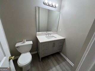 bathroom with vanity, toilet, and hardwood / wood-style floors