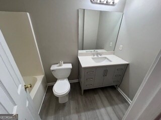 bathroom featuring a bathtub, toilet, hardwood / wood-style flooring, and vanity