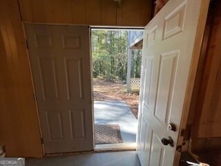 doorway to outside with wood walls