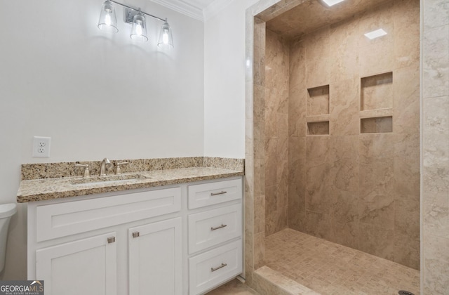 bathroom featuring tiled shower, crown molding, and vanity