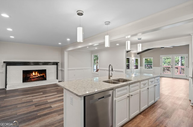 kitchen featuring white cabinetry, dishwasher, sink, an island with sink, and pendant lighting