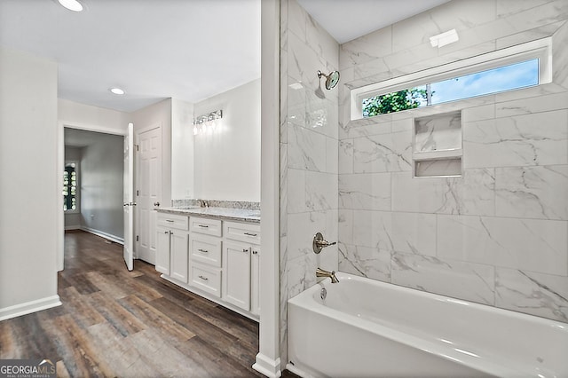 bathroom with hardwood / wood-style floors, vanity, and tiled shower / bath