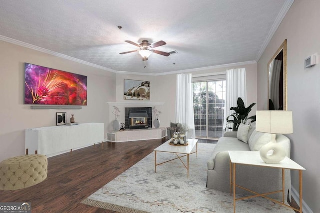 living room with dark wood-type flooring, ceiling fan, a textured ceiling, and ornamental molding