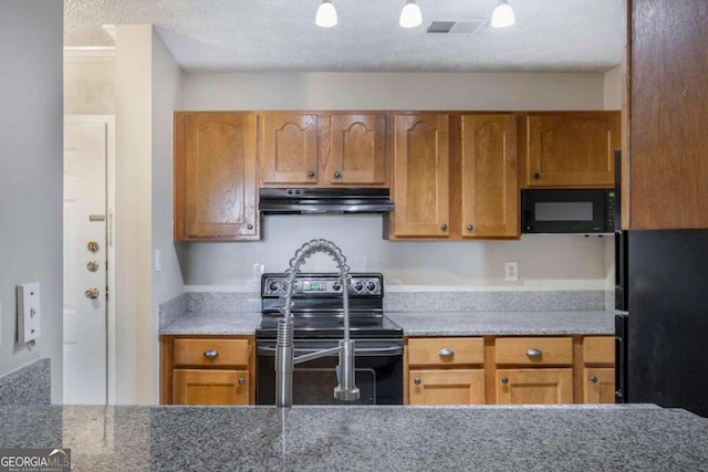 kitchen featuring black appliances, light stone counters, and a textured ceiling