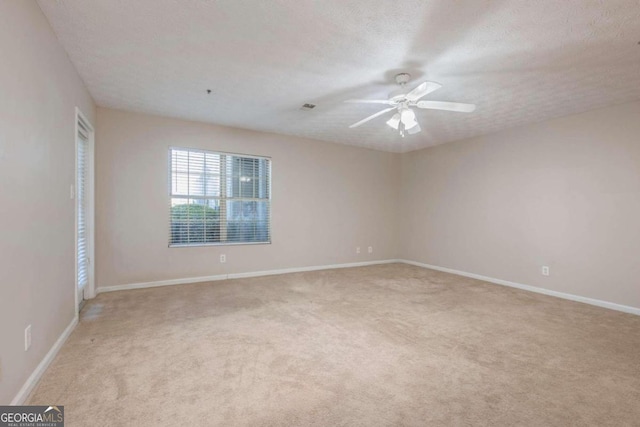 empty room with a textured ceiling, light colored carpet, and ceiling fan