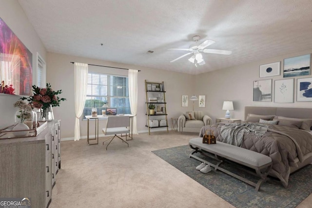 bedroom featuring a textured ceiling, light colored carpet, and ceiling fan