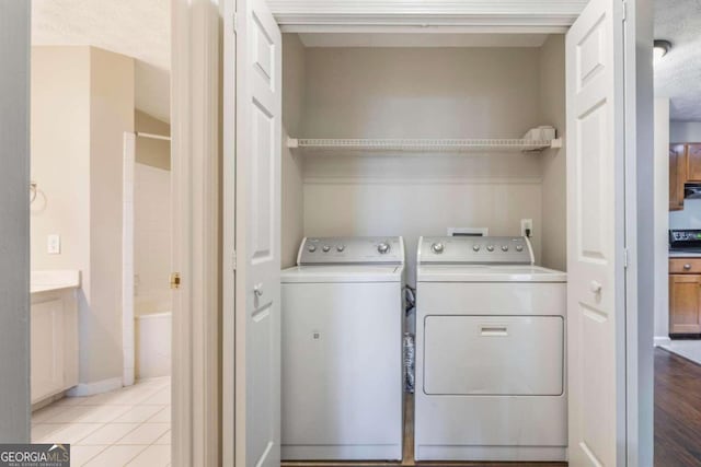 laundry area featuring light hardwood / wood-style floors, a textured ceiling, and washing machine and clothes dryer