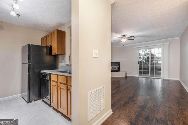 kitchen featuring a textured ceiling, black appliances, light hardwood / wood-style flooring, and a fireplace