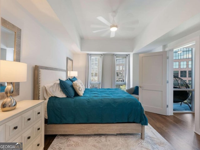 bedroom featuring ceiling fan, hardwood / wood-style flooring, and multiple windows