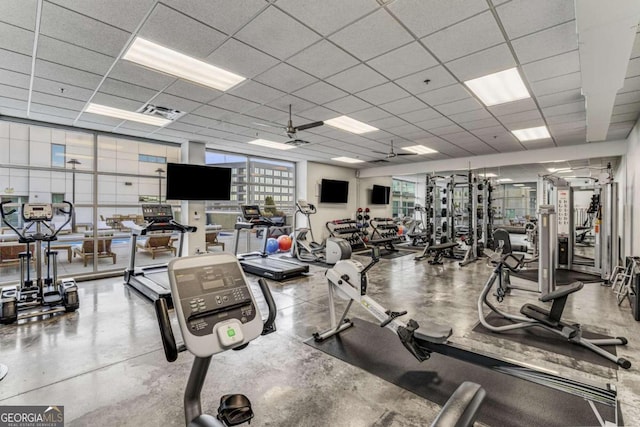 gym with ceiling fan, a paneled ceiling, and concrete flooring