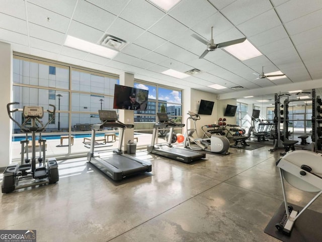 gym featuring a drop ceiling, concrete flooring, and ceiling fan