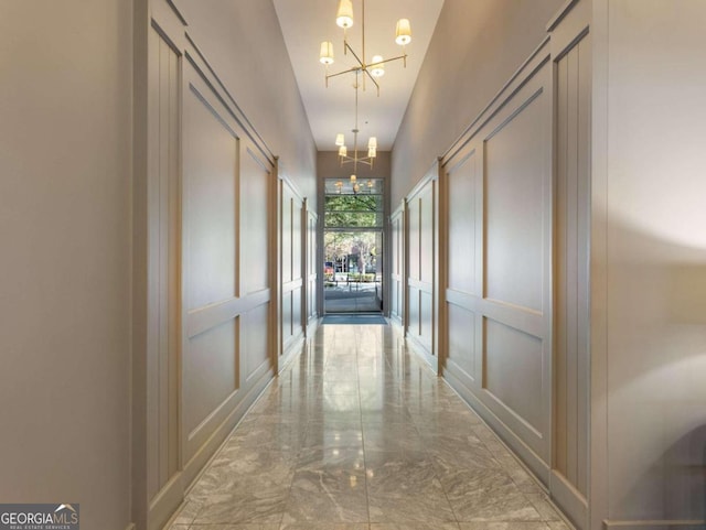 corridor featuring a chandelier and a towering ceiling