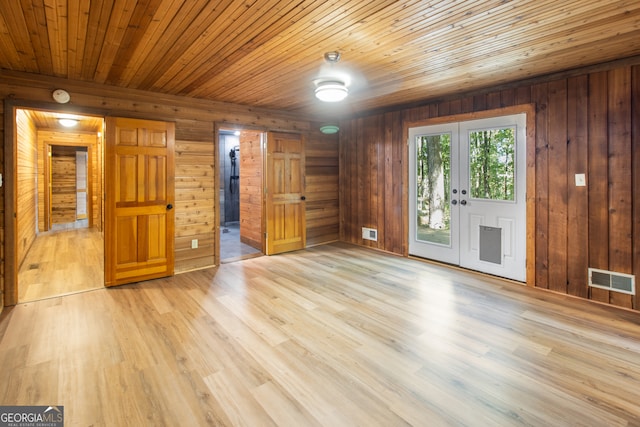 unfurnished living room featuring light hardwood / wood-style floors, french doors, wood walls, and wooden ceiling