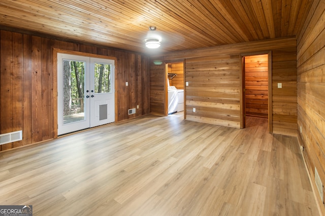 spare room with light hardwood / wood-style flooring, independent washer and dryer, and wooden walls