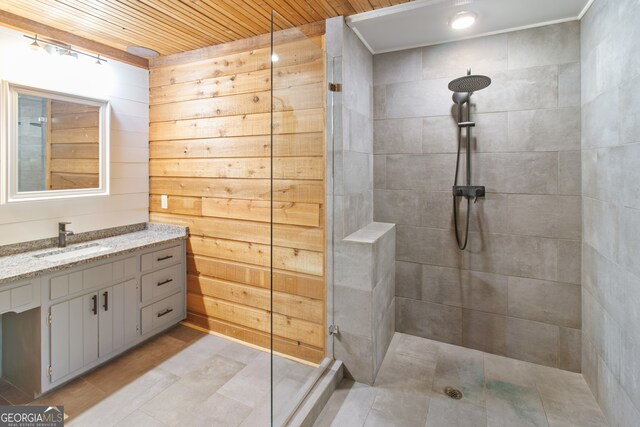 bathroom featuring vanity, a tile shower, wooden ceiling, and wooden walls