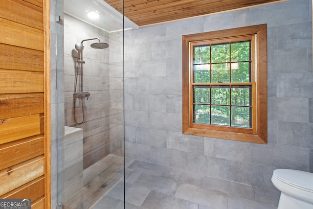 bathroom featuring toilet, tile walls, and tiled shower