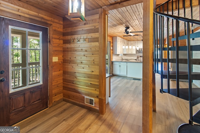 foyer entrance featuring wooden walls, ceiling fan, light hardwood / wood-style floors, and wooden ceiling