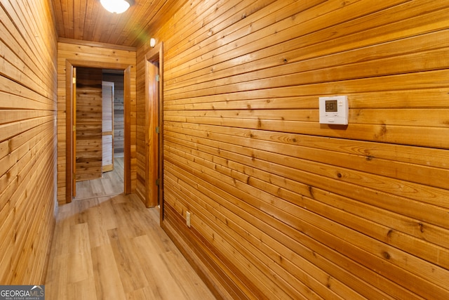 corridor featuring light hardwood / wood-style flooring, wood walls, and wooden ceiling