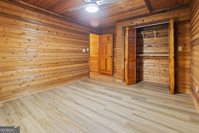 unfurnished bedroom with wood walls, a closet, light hardwood / wood-style flooring, wooden ceiling, and ceiling fan