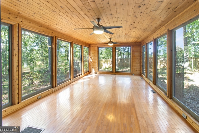 unfurnished sunroom featuring ceiling fan, wooden ceiling, and plenty of natural light