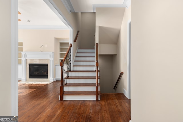 stairs with crown molding and wood-type flooring